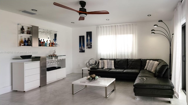 living area with concrete flooring, visible vents, ceiling fan, and a dry bar