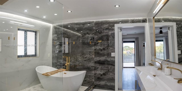 bathroom featuring recessed lighting, vanity, tile walls, marble finish floor, and a soaking tub