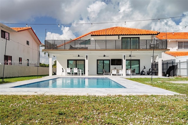 back of property with a balcony, ceiling fan, fence, a patio area, and stucco siding