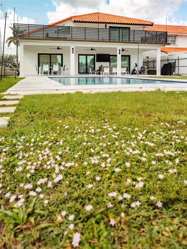 back of property featuring ceiling fan, a patio area, fence, and a balcony