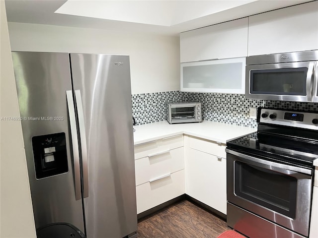 kitchen with dark hardwood / wood-style flooring, backsplash, white cabinets, and appliances with stainless steel finishes