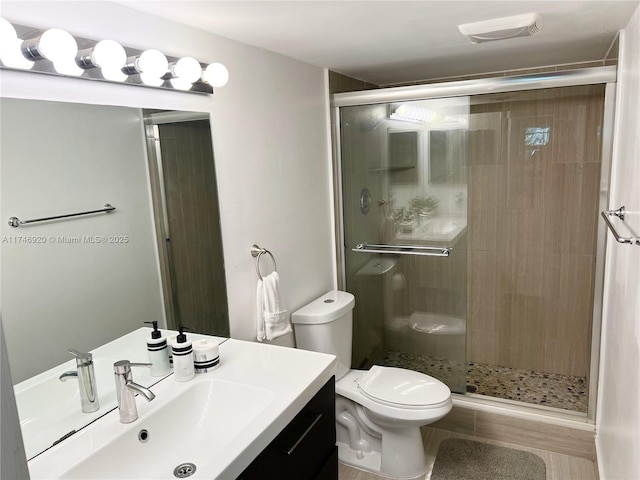 bathroom featuring vanity, a shower with shower door, and toilet