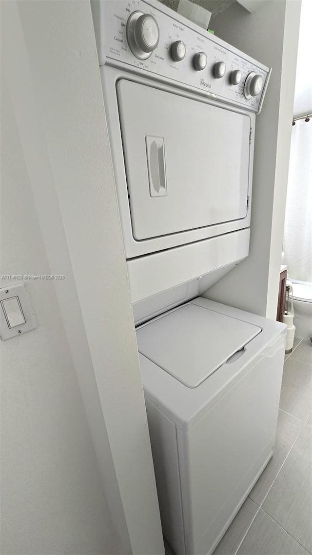 clothes washing area featuring light tile patterned floors and stacked washer / dryer