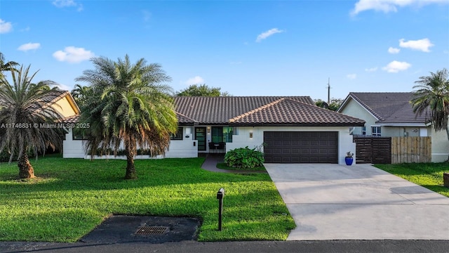 single story home featuring a garage, concrete driveway, a tile roof, a front lawn, and stucco siding