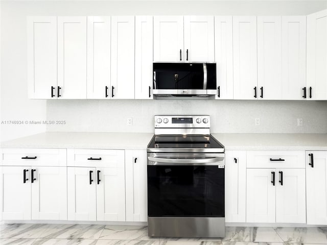 312 SE Via Sangro Prt, St Lucie, FL 34952 - kitchen with appliances with stainless steel finishes, light countertops, light marble finish flooring, and white cabinetry