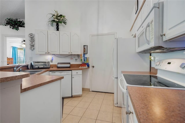 kitchen with light tile patterned flooring, white appliances, a high ceiling, a sink, and white cabinets