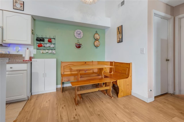 dining area featuring light wood finished floors, baseboards, and visible vents