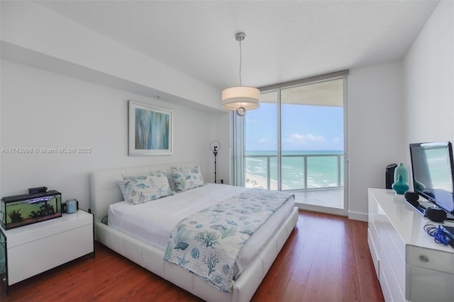 bedroom featuring a wall of windows, access to outside, and dark hardwood / wood-style floors