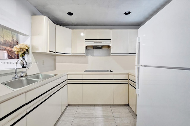 kitchen featuring sink, white fridge, black electric cooktop, white cabinets, and light tile patterned flooring