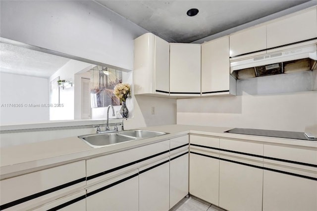 kitchen featuring sink, black electric stovetop, and white cabinets