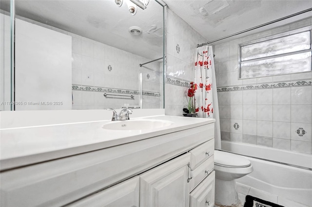 full bathroom with tile walls, shower / tub combo, vanity, and toilet