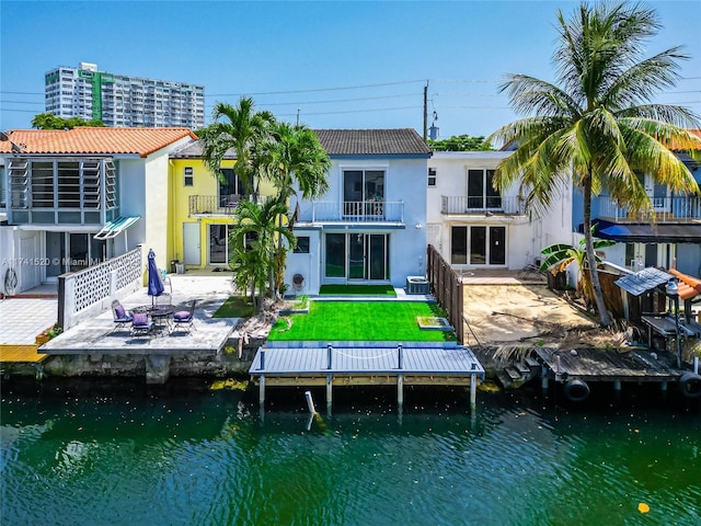 rear view of property with an outdoor fire pit, a water view, a balcony, and a patio area