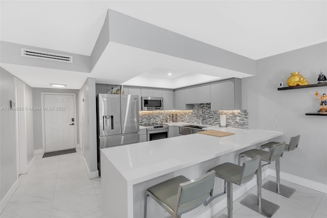 kitchen with sink, a breakfast bar, stainless steel appliances, and kitchen peninsula