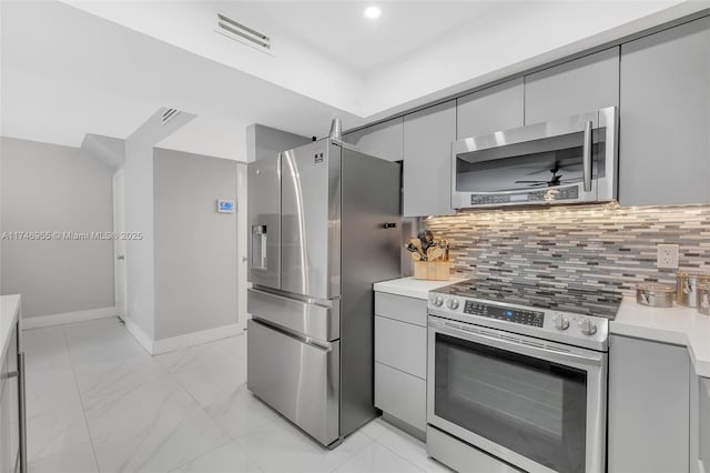 kitchen featuring appliances with stainless steel finishes, gray cabinetry, and decorative backsplash