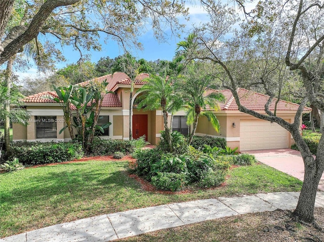 mediterranean / spanish house featuring a garage, a tiled roof, driveway, stucco siding, and a front yard