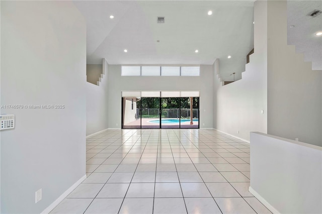 unfurnished room with baseboards, visible vents, a high ceiling, and light tile patterned floors