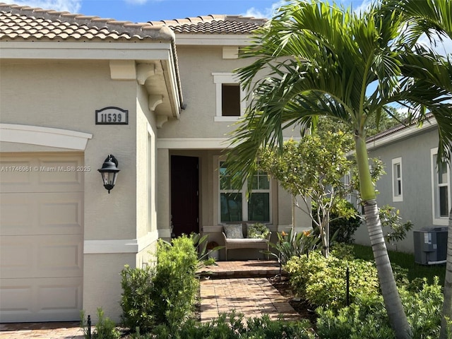 11539 SW Visconti Way, Port St Lucie, FL 34986 - entrance to property with stucco siding, a tiled roof, central air condition unit, and an attached garage