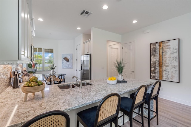 11539 SW Visconti Way, Port St Lucie, FL 34986 - kitchen featuring a sink, stainless steel refrigerator with ice dispenser, a peninsula, light stone counters, and recessed lighting