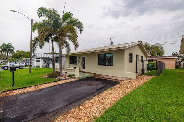 single story home with metal roof, a front lawn, fence, and stucco siding