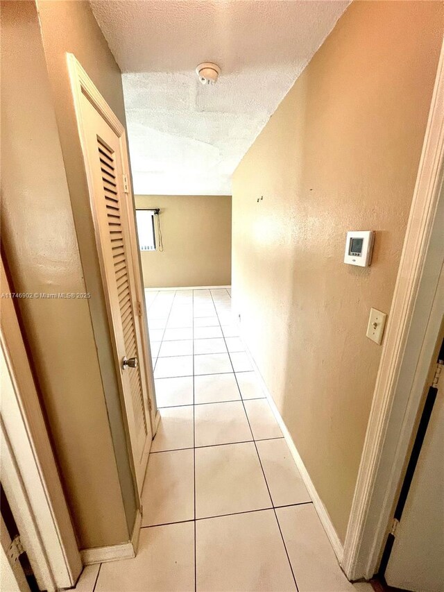 2713 NW 53rd St, Tamarac, FL 33309 - corridor with a textured ceiling, baseboards, and light tile patterned floors