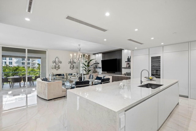 kitchen with a notable chandelier, white cabinets, sink, and a large island