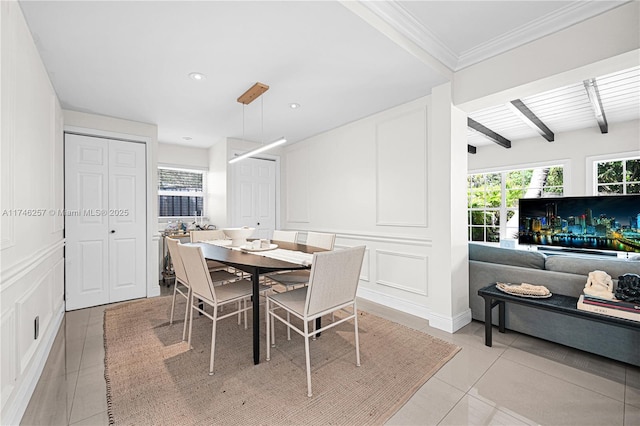 dining space featuring crown molding, a decorative wall, beamed ceiling, and light tile patterned flooring