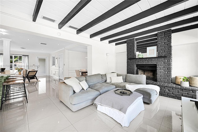 living area with a fireplace, light tile patterned floors, visible vents, beamed ceiling, and ornate columns