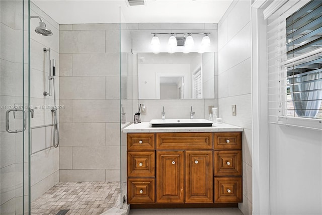 bathroom with tasteful backsplash, tile walls, a shower stall, and vanity