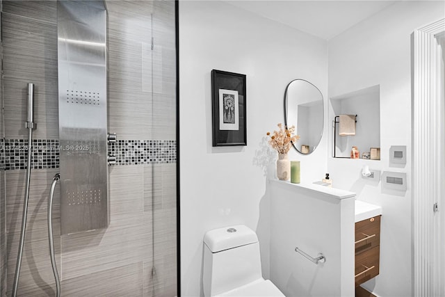 full bathroom with toilet, tiled shower, and vanity