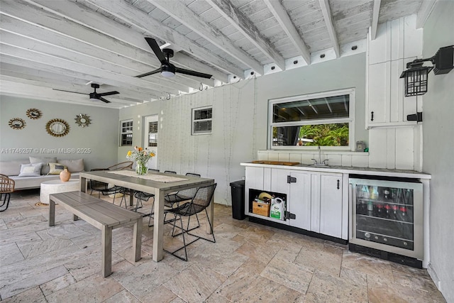 exterior space featuring beverage cooler, beamed ceiling, wood ceiling, and stone tile floors