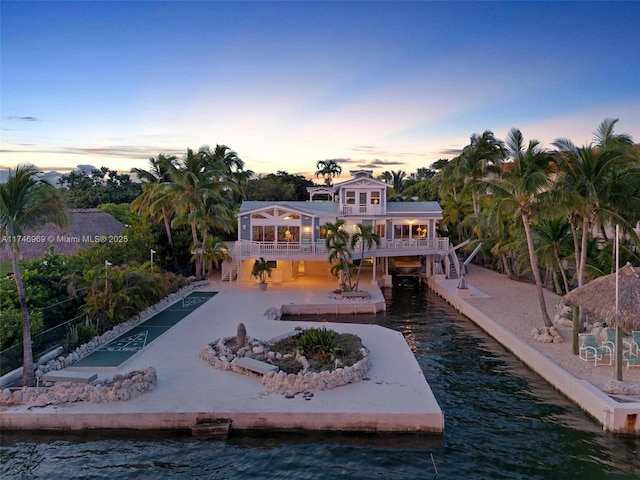 back of property at dusk featuring a patio area and a water view