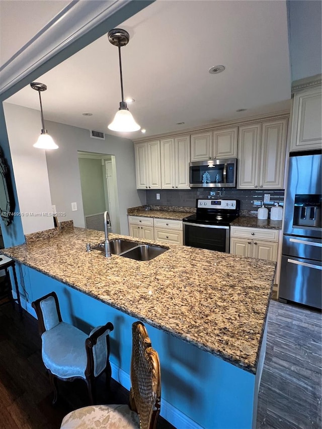 kitchen featuring stainless steel appliances, visible vents, dark wood-type flooring, a sink, and dark stone countertops