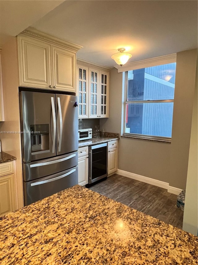 kitchen featuring stainless steel fridge, beverage cooler, dark wood finished floors, glass insert cabinets, and stone counters