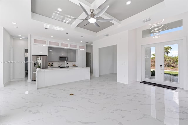 kitchen with stainless steel appliances, white cabinets, a center island with sink, decorative light fixtures, and french doors