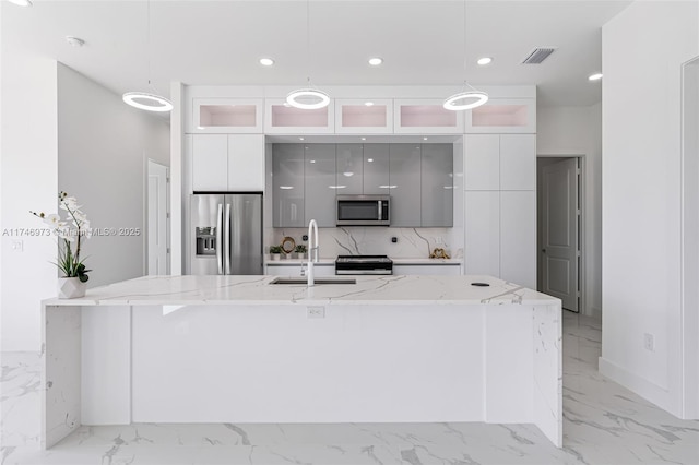 kitchen with a large island, sink, appliances with stainless steel finishes, white cabinetry, and hanging light fixtures