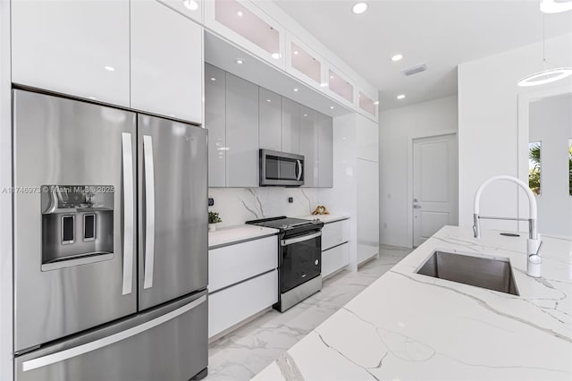 kitchen with white cabinetry, appliances with stainless steel finishes, and pendant lighting