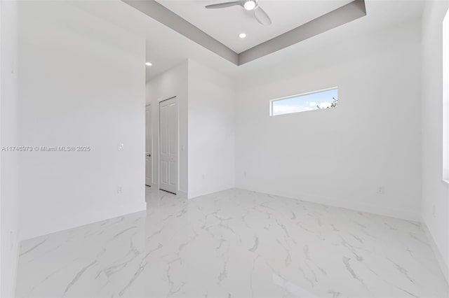 empty room with a raised ceiling and ceiling fan