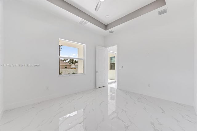 spare room with a tray ceiling and ceiling fan