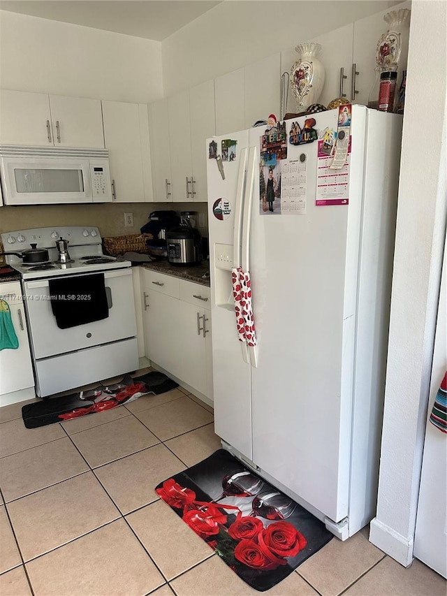 kitchen with white appliances, light tile patterned flooring, and white cabinets