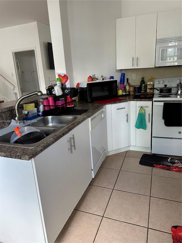 kitchen with white appliances, sink, light tile patterned flooring, and white cabinets