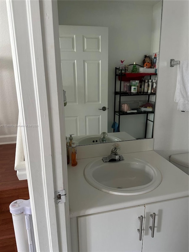 bathroom featuring toilet, wood-type flooring, and vanity