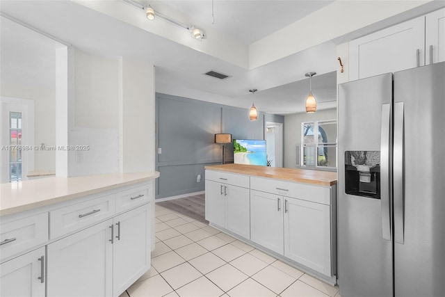 kitchen with white cabinets, stainless steel fridge with ice dispenser, hanging light fixtures, and light tile patterned floors