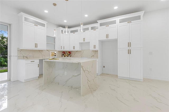 kitchen with light stone countertops, a center island, pendant lighting, and white cabinets