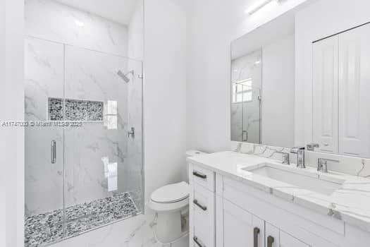 bathroom with walk in shower, vanity, and toilet