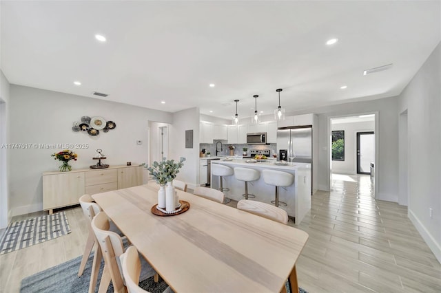 dining space with sink and light wood-type flooring