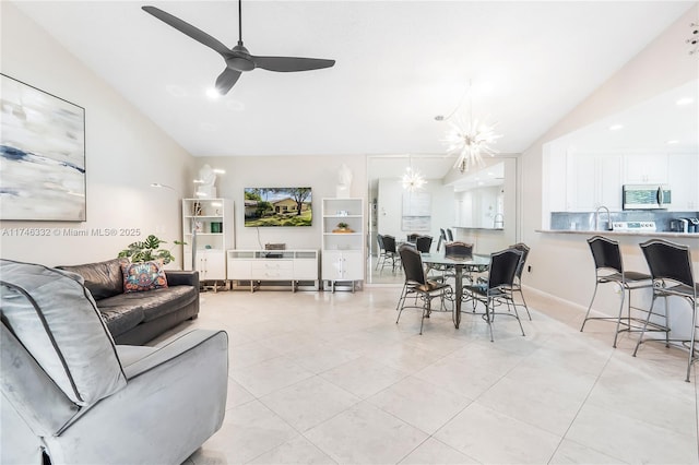 living room with ceiling fan with notable chandelier, vaulted ceiling, and light tile patterned flooring