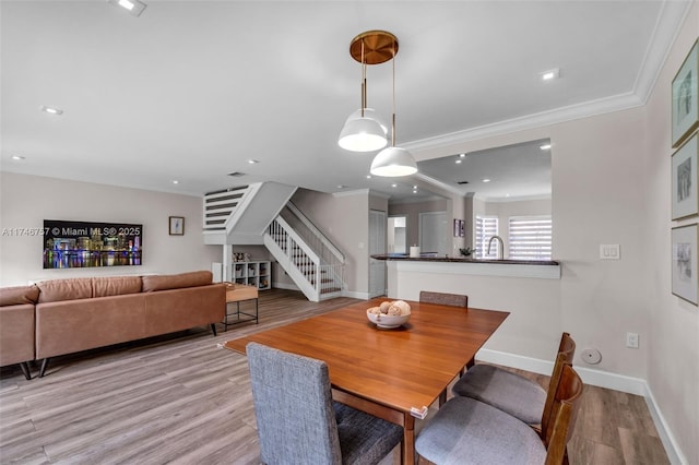 dining area with ornamental molding and light hardwood / wood-style flooring