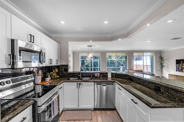 kitchen with white cabinetry, hanging light fixtures, sink, dark stone counters, and appliances with stainless steel finishes