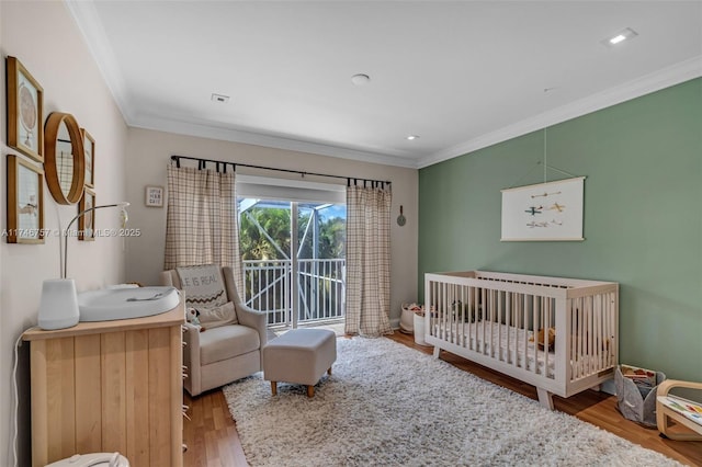 bedroom featuring crown molding, wood-type flooring, and access to exterior