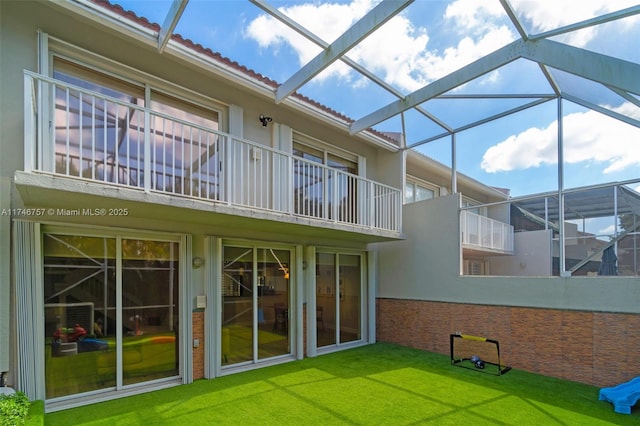 rear view of property with a yard and glass enclosure